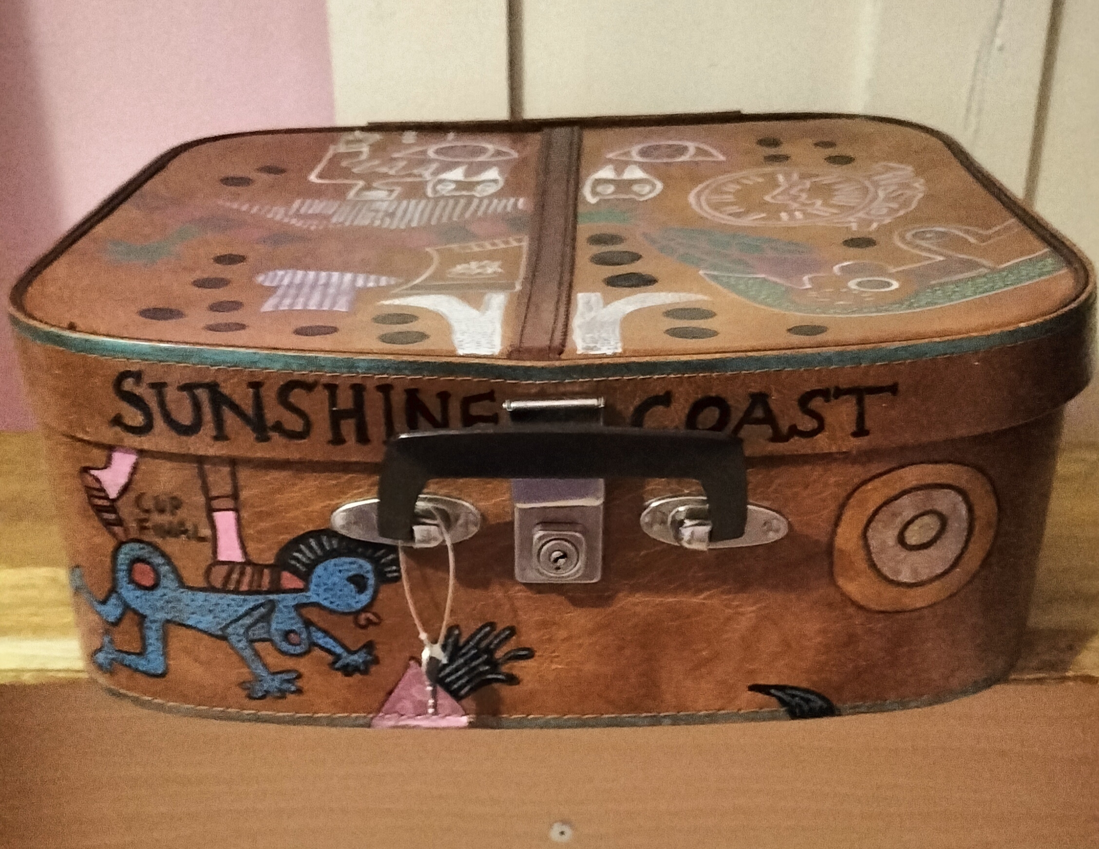 I want your baby daddy hand painted vintage vanity case. This is the top of the case where the lock is. A blue female figure on hands and knees with a footballers legs on top of her with the words Cup Final. Lettering says Sunshine Coast.