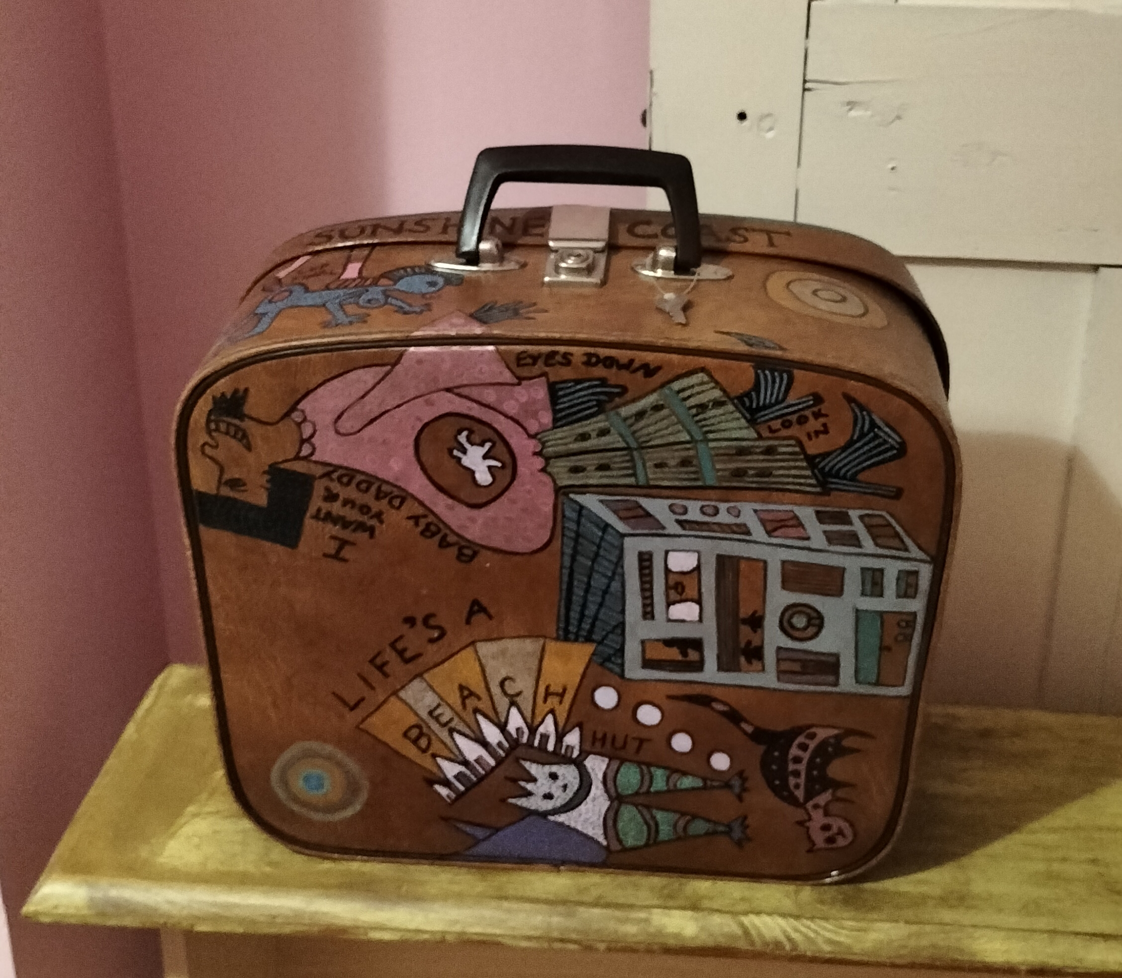 Hand painted vintage brown vanity case. Illustration on all sides. This is the bottom and shows a man with an embryo in thier stomach with the words I want your Baby Daddy. This is referencing the TikTok trend I want your daddy too. Other illustration is abstract animal and the words Life is a Beach hut. A little cat is on this side too.