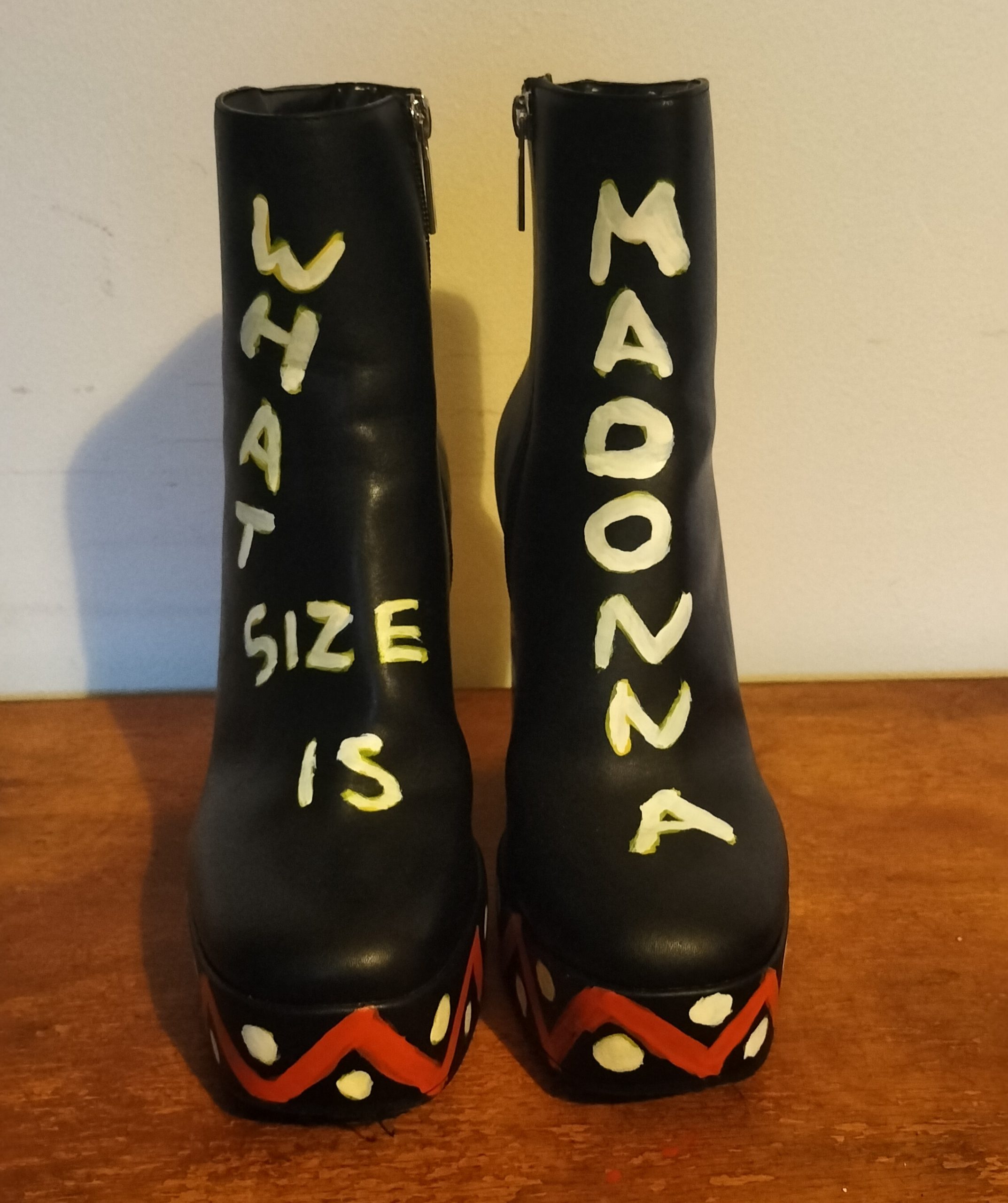 Size 4 black ankle/calf boots.  Upvc.  Lettering across the front of the two boots reads What size is (on one boot) and Madonna on the other.