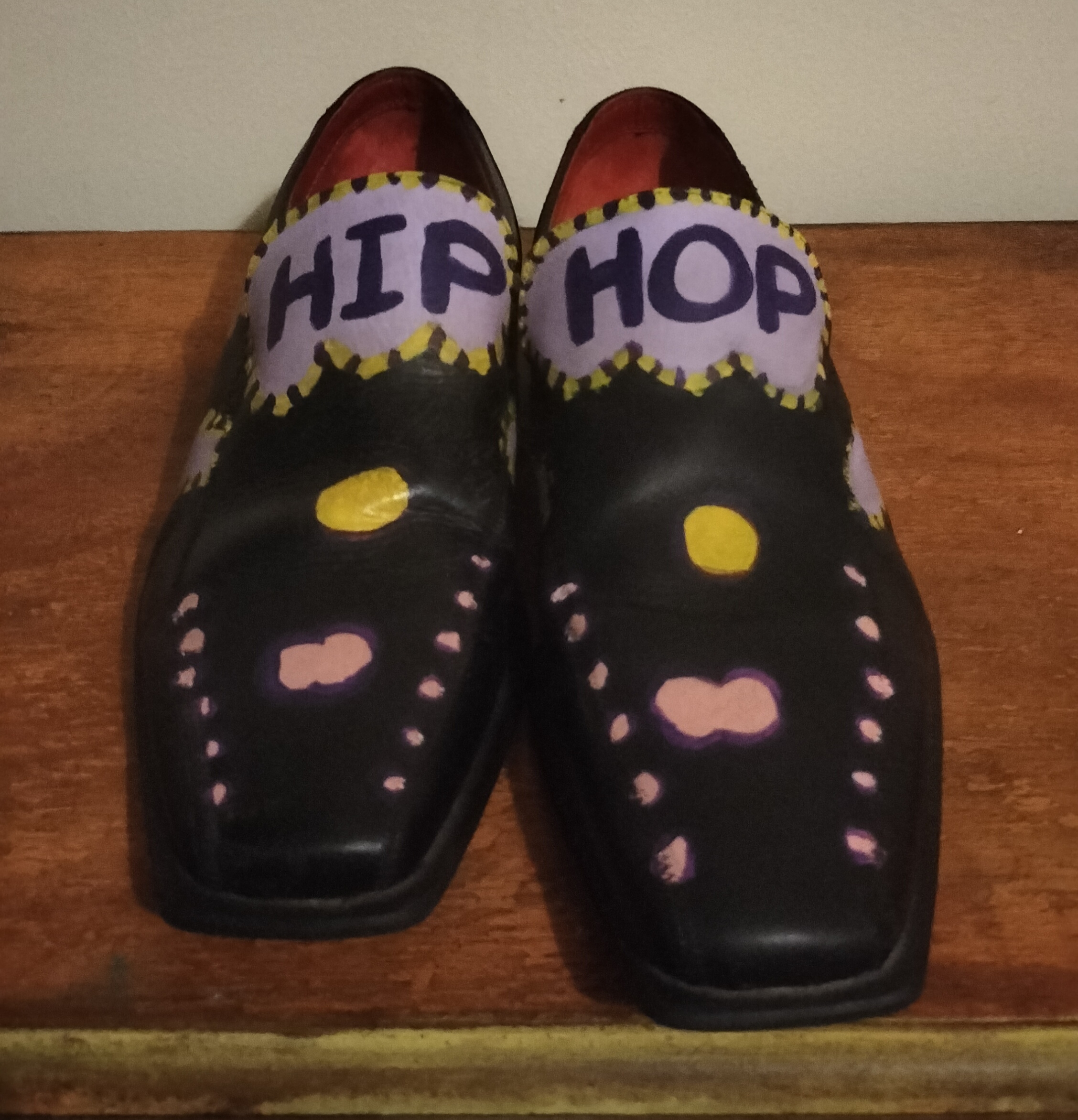 Size 8 slip on leather shoes with the words Hip Hop hand painted on them. Original design using lilac, yellow and black paint. Pink and yellow liver spots on the front. Hip on one shoe and Hop on the other on the top of the front of the shoes which is high on your foot. Turqoise painted on the heels of the shoes and pink liver spots with dark surround. One offs.