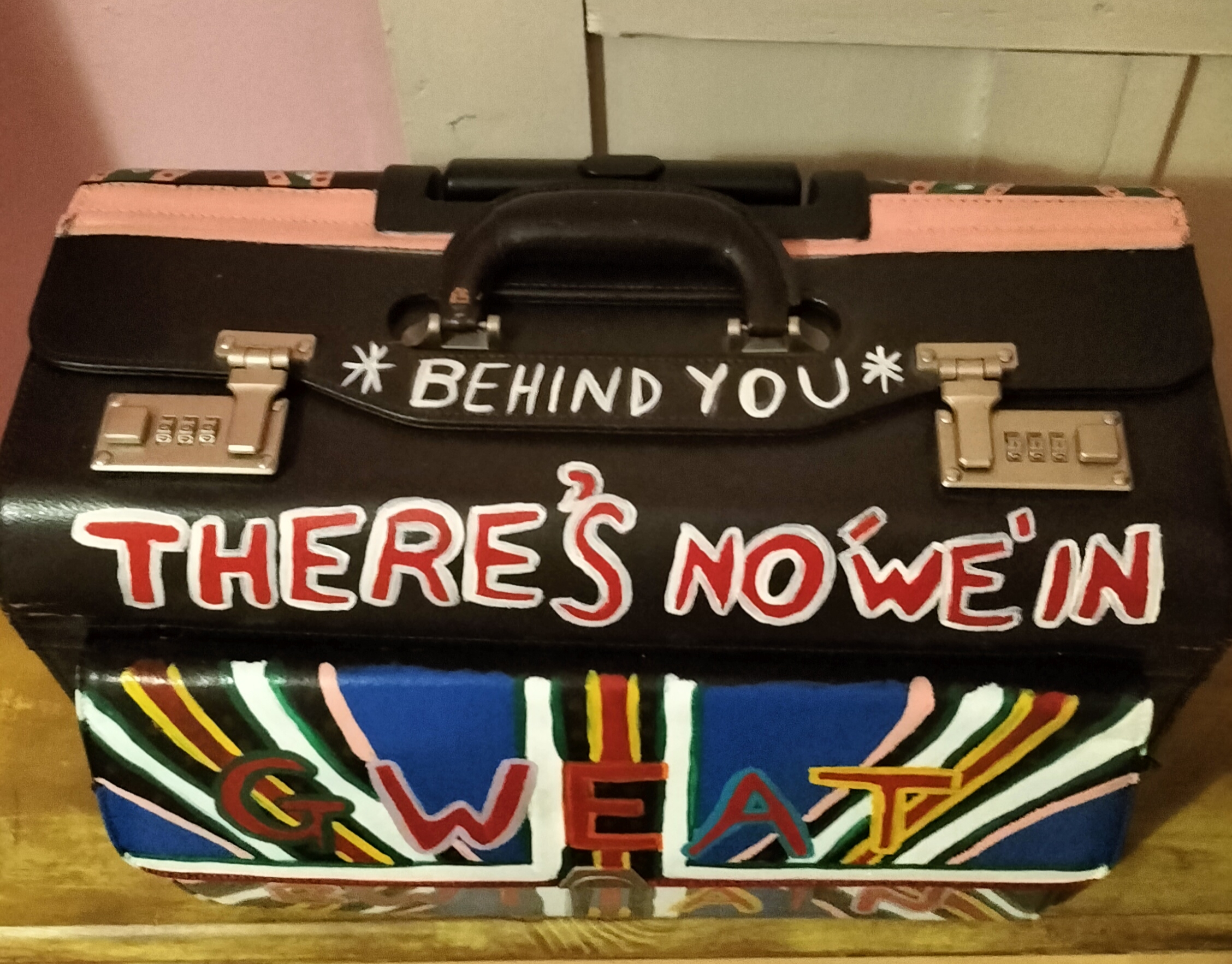 Top of hand painted pilot case with the words Behind You on it. Referencing theatre and panto and on the back of the case is a scene referencing Punch and Judy.