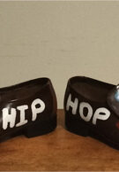 Hand painted brown leather shoes. Slip ons. Flat. Words "Hip Hop" painted on the shoes as well as kidney shapes.