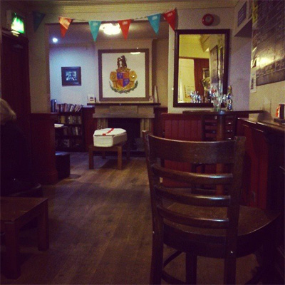 Coffin soft sculpture in a pub. White satin cofin with a red cross on the top representing the St. George's Cross. The work is interactive art work and people are asked what they would be saying goodbye to at the funeral of England. This is about how people identify with England and what it means to them. Poetry and performance has accompanied this work and there is a Condolences Book that people leave comments in as well.