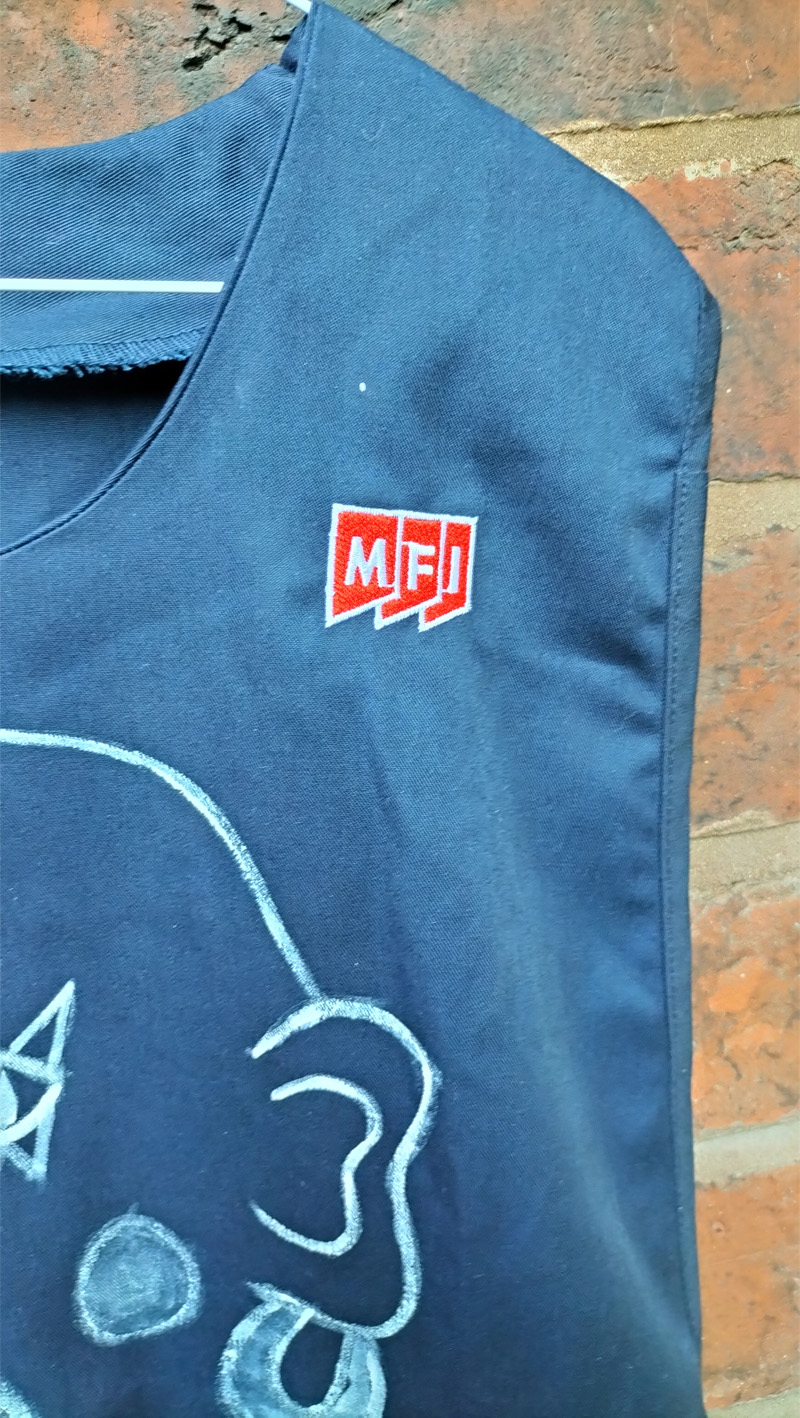 Close up of MFI logo on left front of shoulder. Disco Queen hand painted tabard. Dinner Lady disco style. Art work on the back reads Maam. On the front is a head (abstract style) and the words Disco Queen. Size XXL probably 12 to 14 UK size. £60 in the UK including postage. Navy blue.