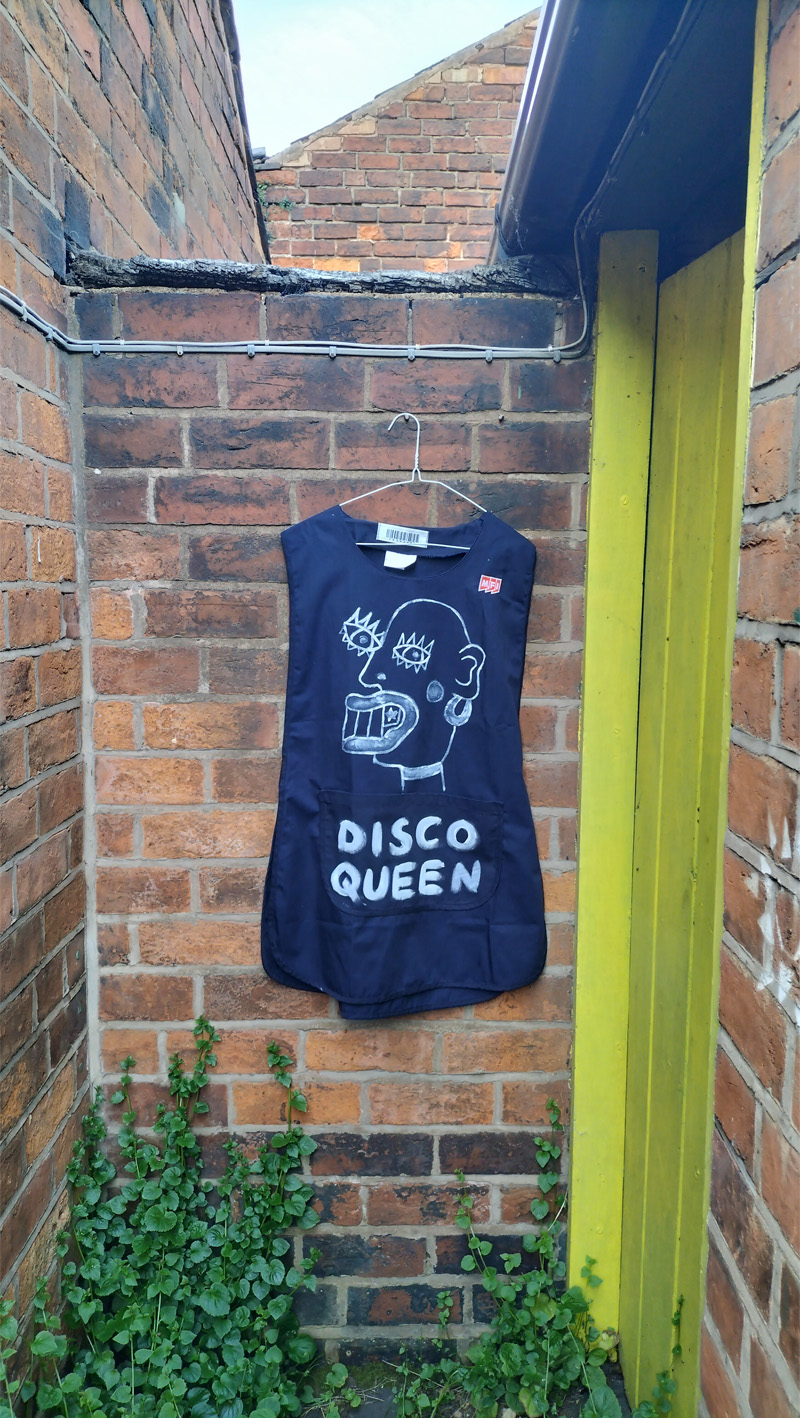 Disco Queen hand painted tabard. Dinner Lady disco style. Art work on the back reads Ma’am. On the front is a head (abstract style) and the words Disco Queen. Size XXL probably 12 to 14 UK size. £60 in the UK including postage. Navy blue.