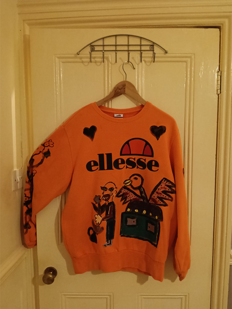 Ellesse orange size 16 sweatshirt. Hand painted front, back and sleeves. Front has illustration of abstract bird on sideboard alongside a figure holding a p;lant and flower and a little pot with flower coming out of it to the left. One sleeve has a vine-like design with monkeys in black outline paint and the other sleeve has black hearts on it. The back has the word "Brutal" and an abstract animal like a dog and a large boot with heel with squares looking like windows in a high rise flat. One off design.