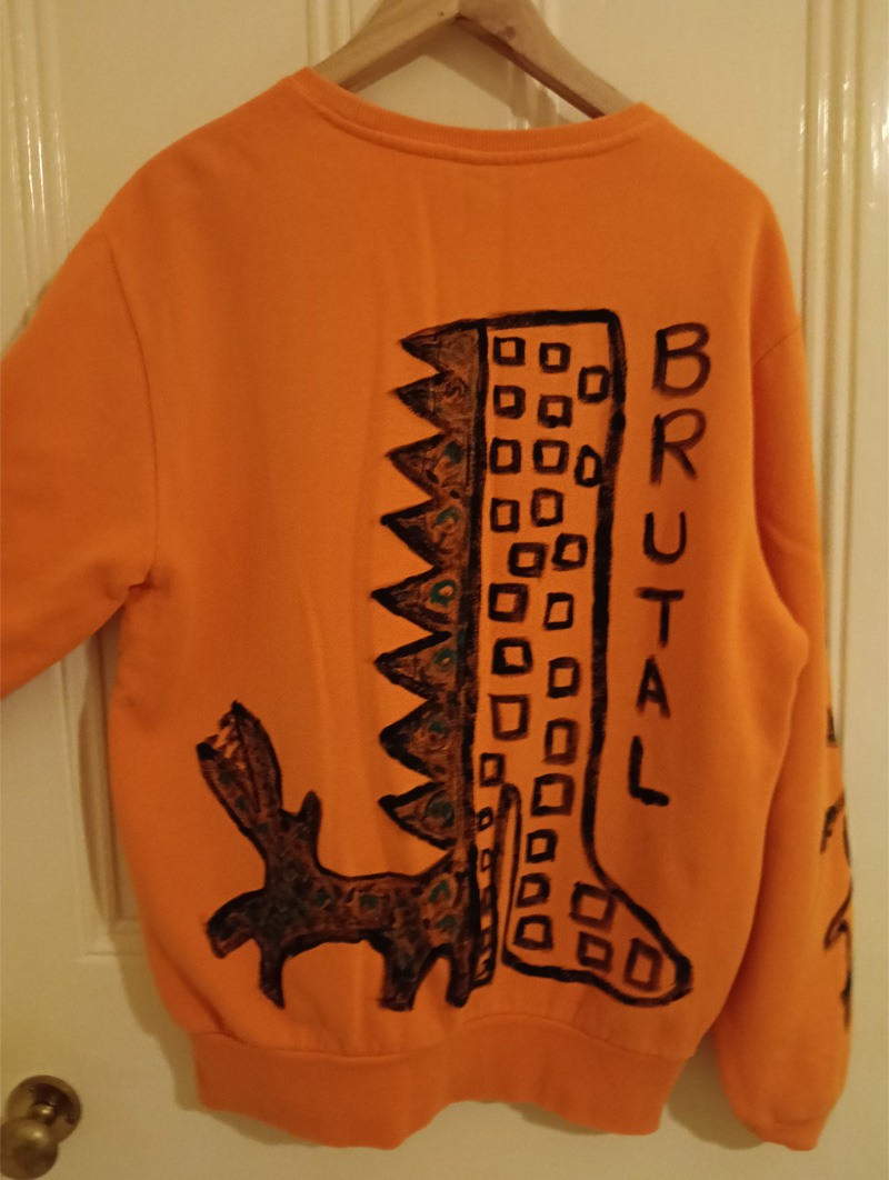 Ellesse orange size 16 sweatshirt. Hand painted front, back and sleeves. Front has illustration of abstract bird on sideboard alongside a figure holding a p;lant and flower and a little pot with flower coming out of it to the left. One sleeve has a vine-like design with monkeys in black outline paint and the other sleeve has black hearts on it. The back has the word "Brutal" and an abstract animal like a dog and a large boot with heel with squares looking like windows in a high rise flat. One off design.