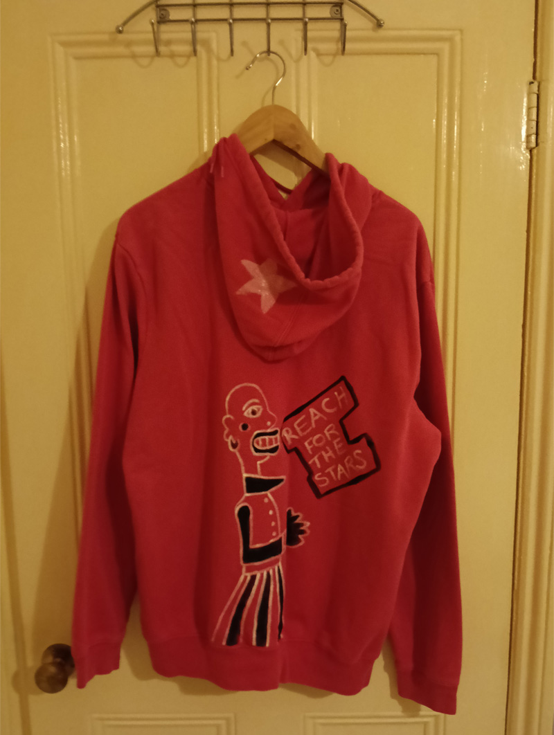 Gap hoodie size 16. Pink. Hand painted on the front. Woman figure around the A of the word Gap. Shows gap at top of legs which is referencing a woman's weight and space between her thighs. Sideboard to the left of the legs and shoes. Knee length socks. Dog to the right of the legs. Plant with leaves and flower on top of the sideboard. Vintage hoodie. Painted front and back. Back of hoodie has a star ont he hood and a figure on the back of the hoodie which is abstract, bald headed and the words Reach for the Stars appear in a box outline.Gap hoodie size 16. Pink. Hand painted on the front. Woman figure around the A of the word Gap. Shows gap at top of legs which is referencing a woman's weight and space between her thighs. Sideboard to the left of the legs and shoes. Knee length socks. Dog to the right of the legs. Plant with leaves and flower on top of the sideboard. Vintage hoodie. Painted front and back. Back of hoodie has a star ont he hood and a figure on the back of the hoodie which is abstract, bald headed and the words Reach for the Stars appear in a black line surround.