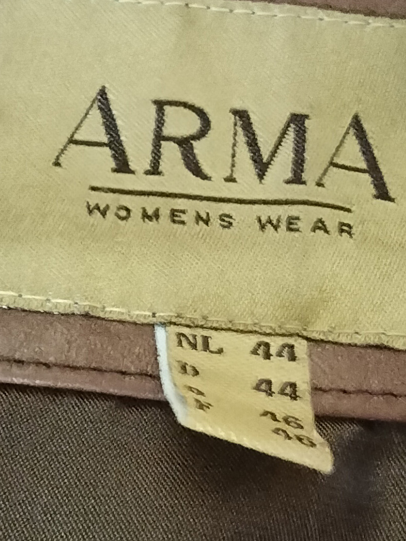 Back of jacket is hand painted. Figure on the left is wearing a skirt and top. Bald headed and carrying a handbag. Knee high socks and orange platform shoes. Smaller figure balancing on the main figure's shoulder and the top of a high backed chair. Similar shoes and trousers and top. Also bald headed. The words "Oxford Bags" across the trousers and between the legs below reads "+ easy shags". Blue chair. Words underneath the chair read "thoughts rocking dangerously on the back of a chair." Only painted on the back of the jacket. Buttoned up front. A slanted pocket to the left and right of the jacket. Arma leather jacket size 16. Brown.