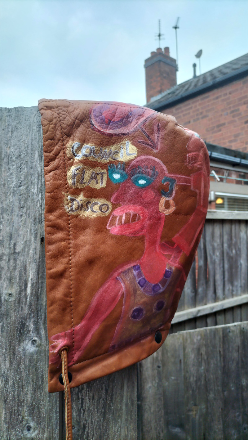 Liam's Old Coat - hand painted vintage parka jacket with hood (brown). One side of detachable hood. Character with a smaller character stood on their shoulders. Words read "Council Flat Disco". Vintage Rome Peabody Massachusetts USA Size 42 brown leather hooded parka jacket handpainted one off.