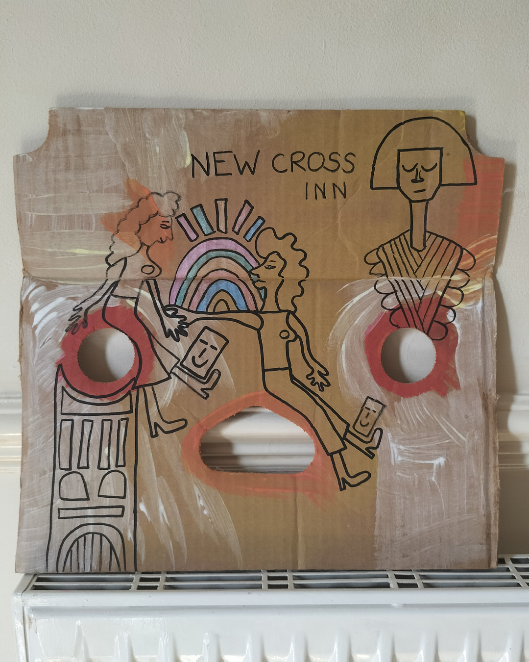 Art work on cardboard. One off. About A3 in size. Square in shape with two round holes (one on each side) and another kidney shaped hole in the middle of the card. The top left and right side of the card are like they have had a semi circle removed. Background: white and orange paint in parts as well as red paint. Two women holding hands, one reaching out to the other. One looks like she is sat on a tall object with a kind of mosaic surface. A bit like a tower. A kind of Pharoah-like figure at the top right of the art work. Blue and pink objects forming some kind of arch and then some oblong shapes above. Colours are alternated throughout. A little card shape with a smiling face near the one foot of each of the women. The art work is about a live music venue in South East London, the New Cross Inn.
