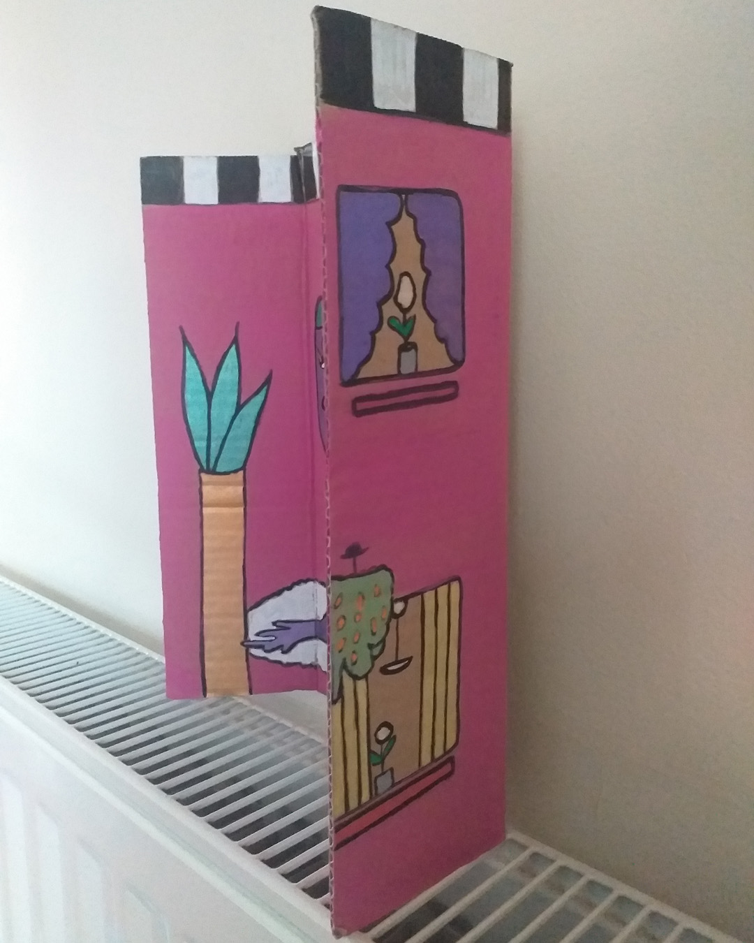 One for the lovers of Cilla Black piece uses some of the words of her song. Step inside love - and stay, I want you to stay cardboard art. About A4 landscape in size folded into three panels. When closed the front of the piece is like the front of a house. When opened it is a image of a purple woman on a rug with a cat and a plant. Front reads Step inside love. Inside reads and stay and lower down the image reads I want you to stay. The back of the image when opened out has painted parts on the left and right of the card and the centre piece is plain cardboard with a sticker on it. Step inside love on the front of the piece. Inside reads … and stay … I want you to stay.