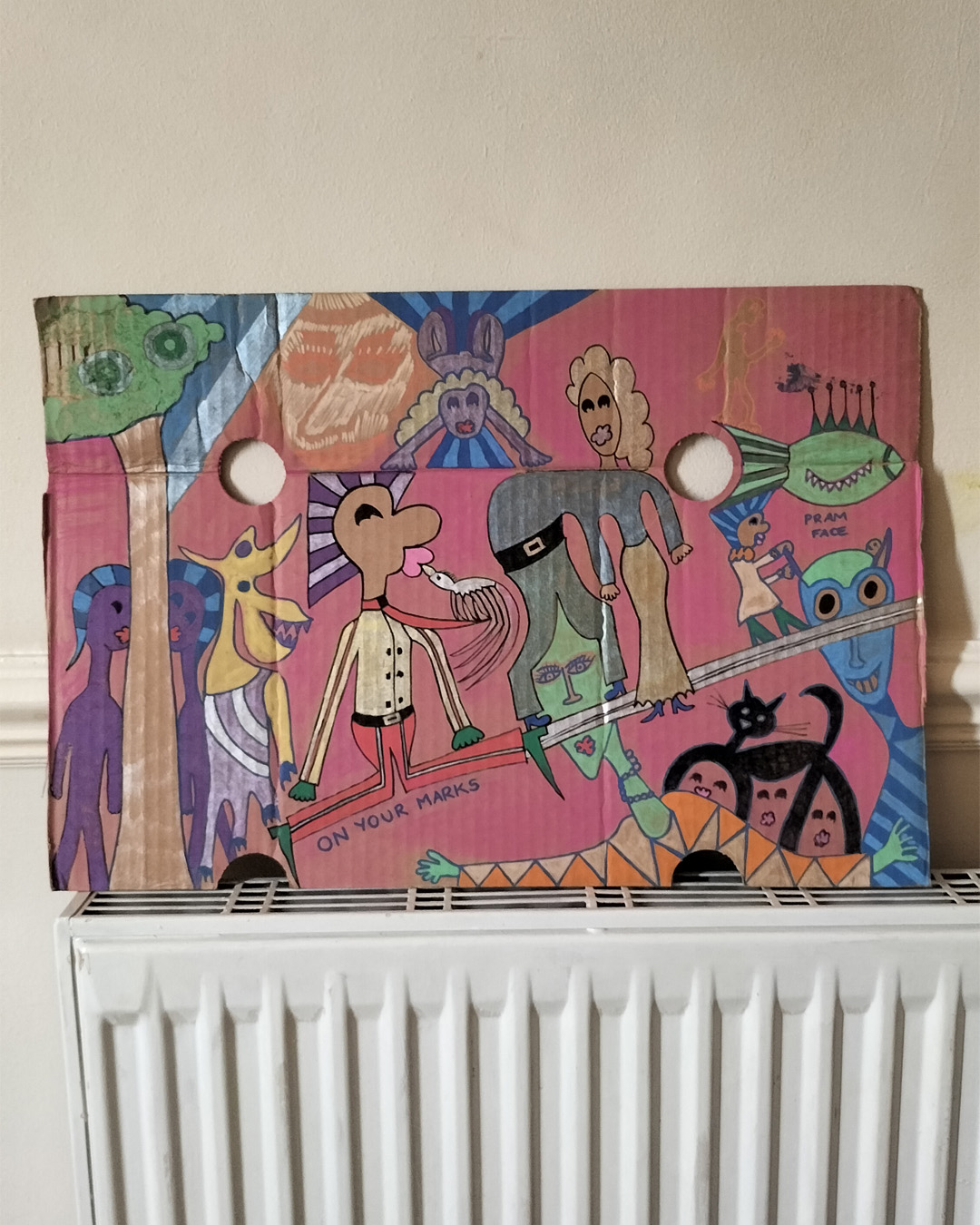 Art work on cardboard. One off. About A3 in size. Two round holes in the cardboard in the top third, one each side of the cardboard. Background: pink paint. A mix of people some merging into one. Cats legs become the hair above faces. A man on his knees is being kissed by a bird where the beak is like a whistle and the words underneath the man’s legs read On your marks. Pram Face are the words above a woman pushing a baby in a pram and the pram wheels are the eyes of a face. There is a fish above the woman pushing the pram. Fantasy figures. Two purple figures with blue two tone hair are peeping out from behind a tree trunk and there is a kind of animal next to them in some kind of full body leotard outfit perfect for sport. One figure bends over and the long blonde hair (seen from the back) is then the skirt of another figure. One off art work.