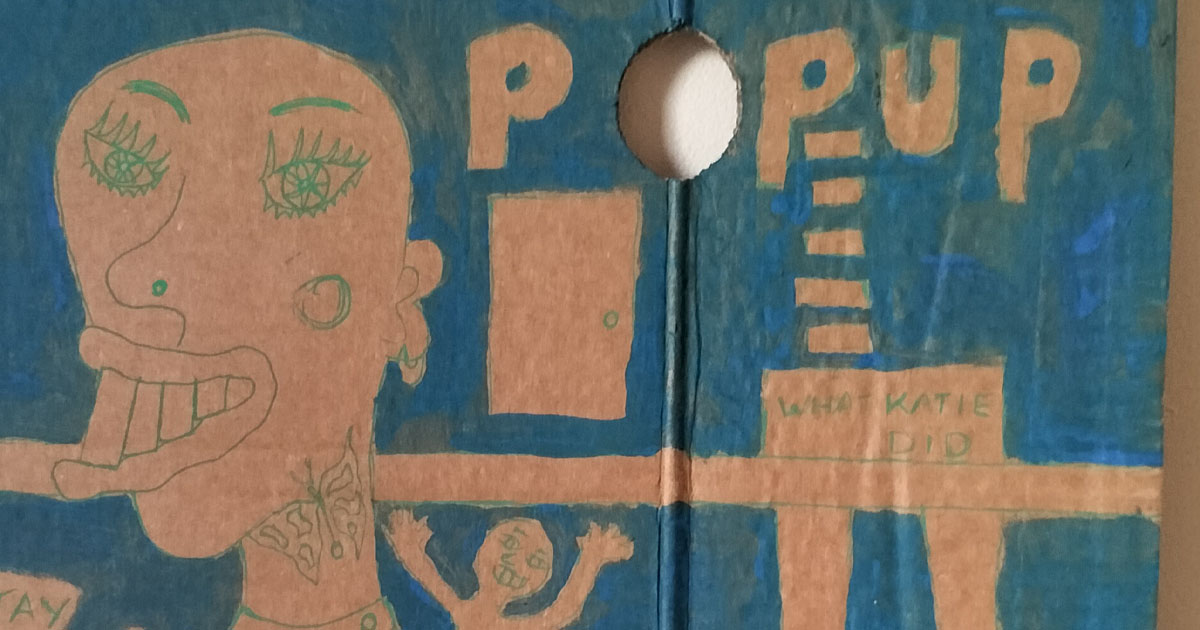What Katie did cardboard art. A3. Large figure on left lifting a weight. Bald head. Quirky drawing. Small figure on shoulder waving. Could be alter ego, could be a memory or that little niggling thought. Image has a horizontal strip across it, not high. On the right of image lower half of woman's body. Reads "What Katie did" on the area for pants and below legs with ankle high bootgs/shoes. Reads Pop Up above and a hole in the cardboard where the O is. There a door above the line too. Blue backgound and figure and drawing do not have any colour inside, just outlines. One-off.